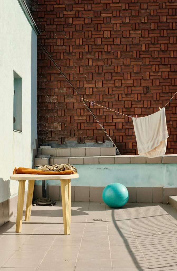 A terrace with brick wall, laundry drying, and a table in the sun.