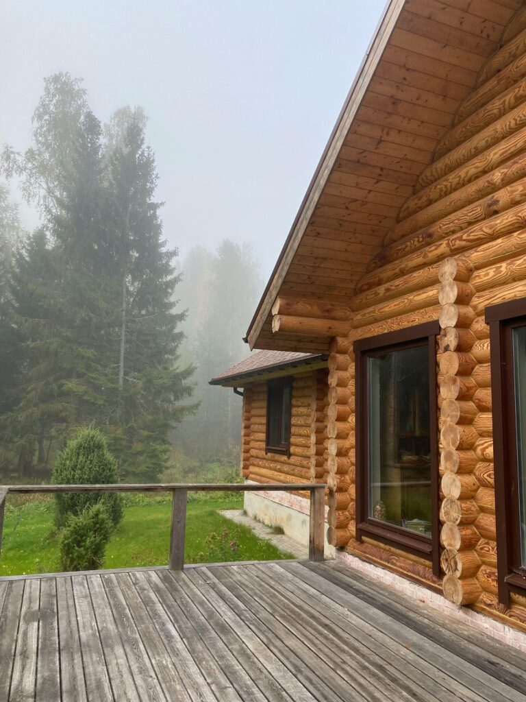 A rustic wooden cabin surrounded by fog and forest, creating a serene and mysterious atmosphere.